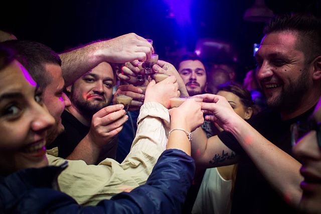 A group of friends toasting with shots in a dimly lit bar, celebrating a night out.