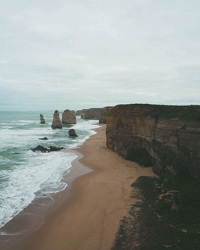 Scenic view of the Twelve Apostles rock formations along the Great Ocean Road coastline in Australia on a cloudy day.