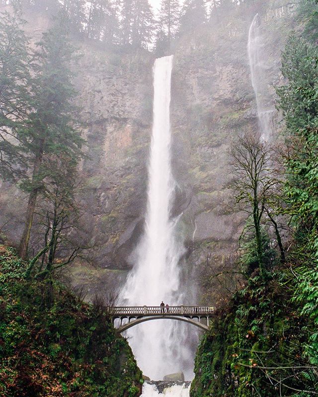 A scenic view of Multnomah Falls with a bridge and people in the Columbia River Gorge, Oregon.