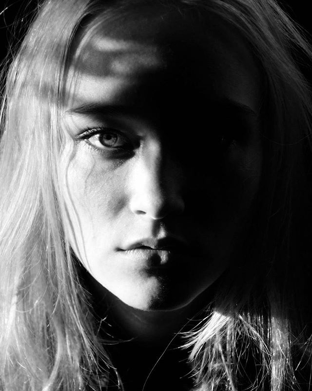 A woman's face is dramatically lit in black and white for a striking, emotional portrait.