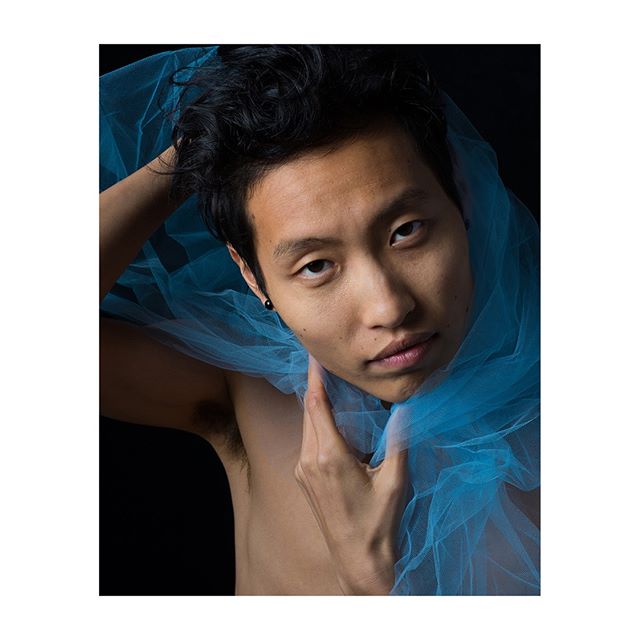 Artistic portrait of an Asian man with a blue veil in a studio setting. Ideal for beauty or fashion campaign.