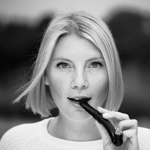 A black and white portrait of a woman with short blonde hair holding a pipe.