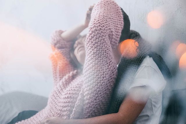 A couple embraces intimately in a soft, dreamy setting filled with bokeh lights, creating a warm, affectionate moment.