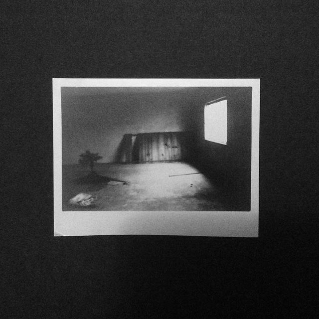 Monochrome shot captures an empty room with a window, creating a moody, vintage atmosphere.