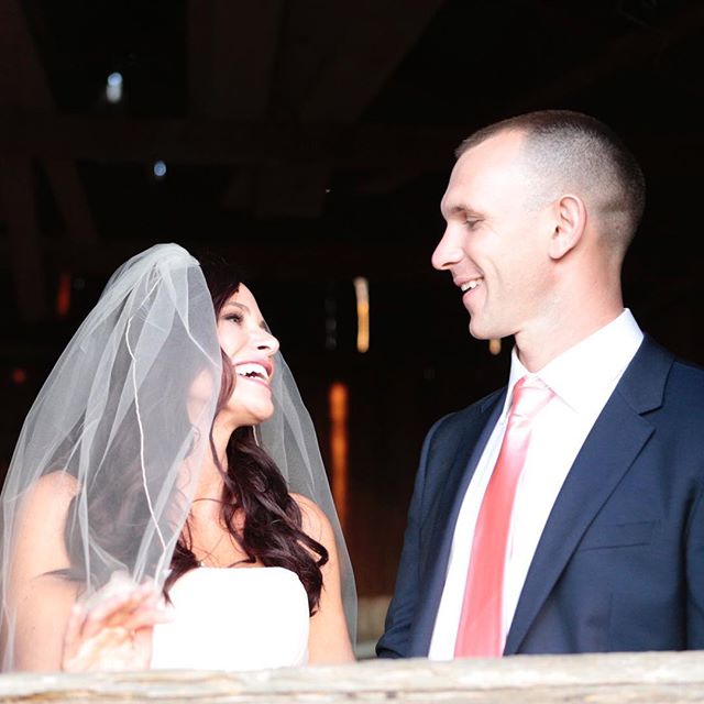 A bride and groom share a happy moment, smiling at each other on their wedding day.