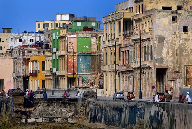 A cityscape view in Havana, Cuba, with colorful buildings and people along the seafront.