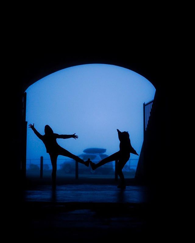 Two silhouetted figures playfully interact within a tunnel, creating a dynamic and artistic composition.