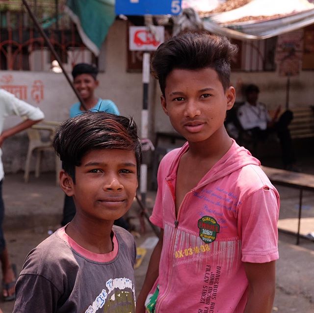 Three young boys pose in a candid street scene, sharing smiles and a glimpse into everyday life.