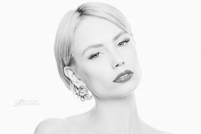 Elegant black and white portrait of a woman with sophisticated style and striking earrings.
