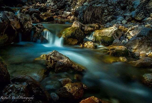 A tranquil river flows over rocks covered in moss, creating a serene and natural landscape.