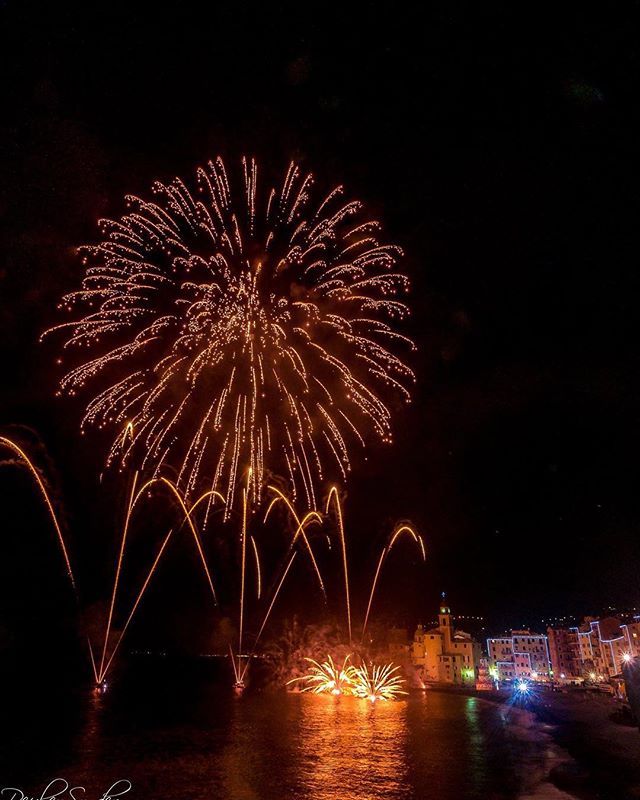 Fireworks light up the night sky over a charming coastal town.