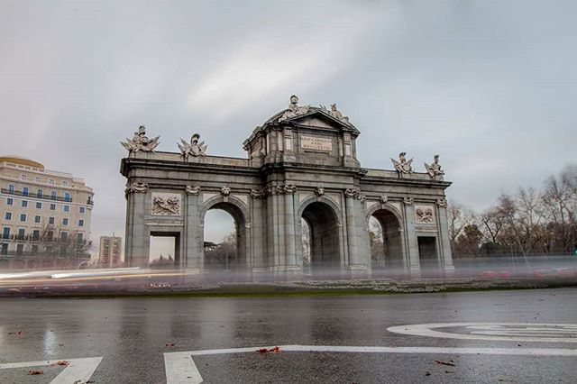 Puerta de Alcalá in Madrid, Spain, under a cloudy sky. A beautiful architectural monument in the city.