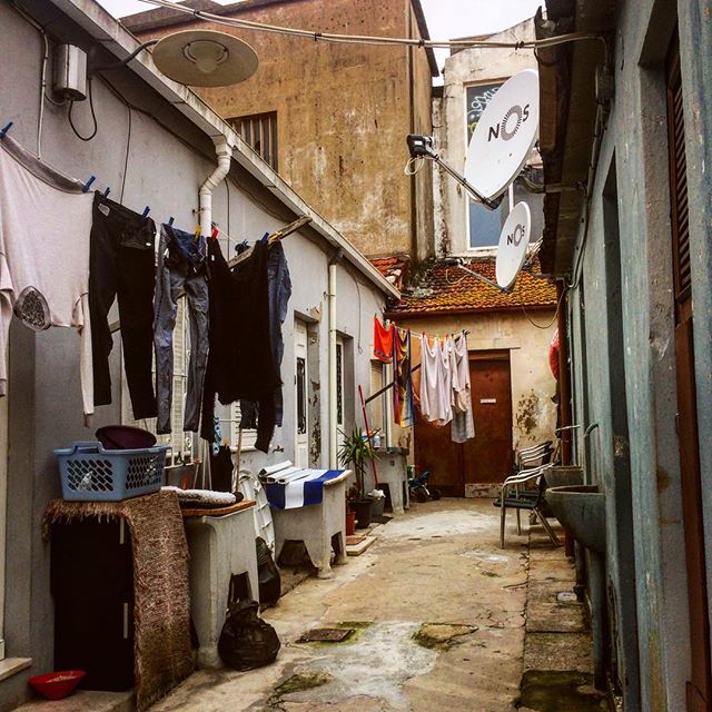 An urban alleyway scene shows laundry hanging between buildings, offering a candid glimpse into daily life.