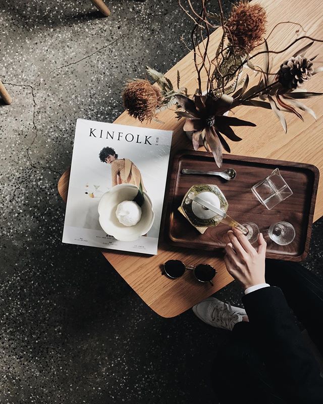 Overhead shot of a table setting with tea, a magazine, and sunglasses, ideal for editorial or social media.
