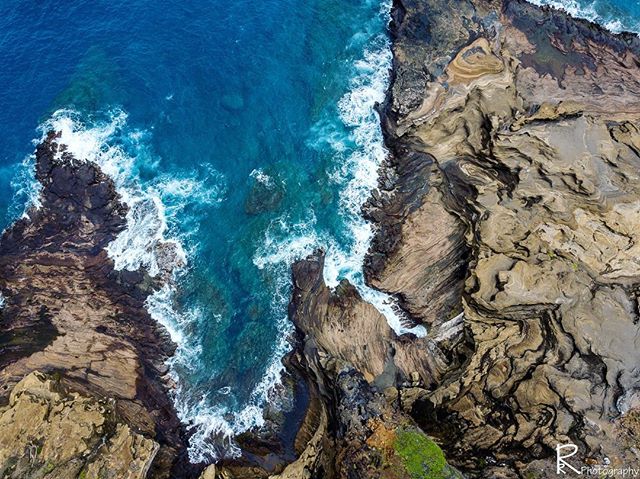 Aerial view of waves crashing against the rocky coastline, creating a serene and beautiful seascape.