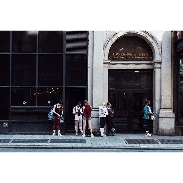 Six people stand outside the Lawrence A. Wien Center on a city street.