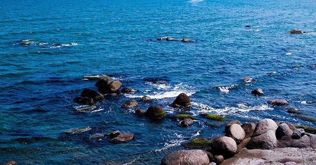 Waves gently crash over rocks in a serene seascape, perfect for backgrounds, travel, or website visuals.