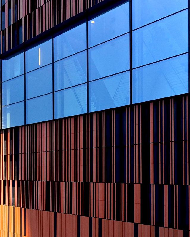 Modern building facade with blue windows and vertical brown and black stripes. Great for architectural and urban themes.