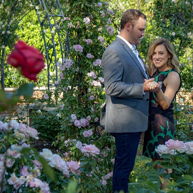 A happy couple shares a dance in a beautiful rose garden, celebrating love and joy.