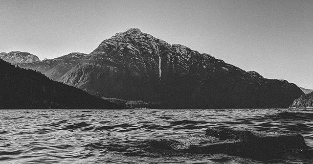 A black and white landscape featuring a mountain and rippling water, conveying peace and natural beauty.