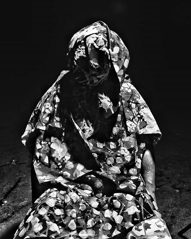 An artistic monochrome portrait of a hooded figure against a dark background, creating a mysterious and contemplative mood.