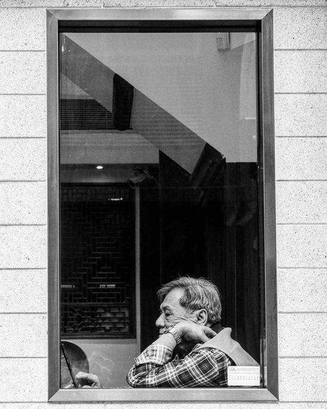 A man sits by a window, lost in thought, reflecting on life in monochrome.