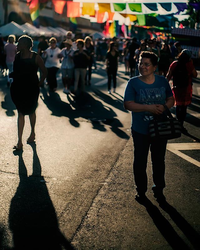 People enjoying a lively street fair, casting long shadows in the sun.