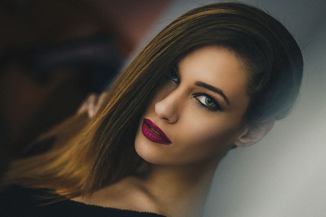 A stunning portrait of a woman with captivating green eyes and bold red lipstick.