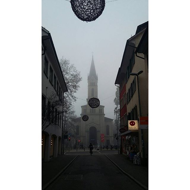 A street view featuring a church in the distance under a thick fog.
