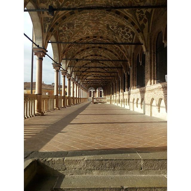 A long, covered arcade with ornate columns and ceilings creates a serene and historical atmosphere.
