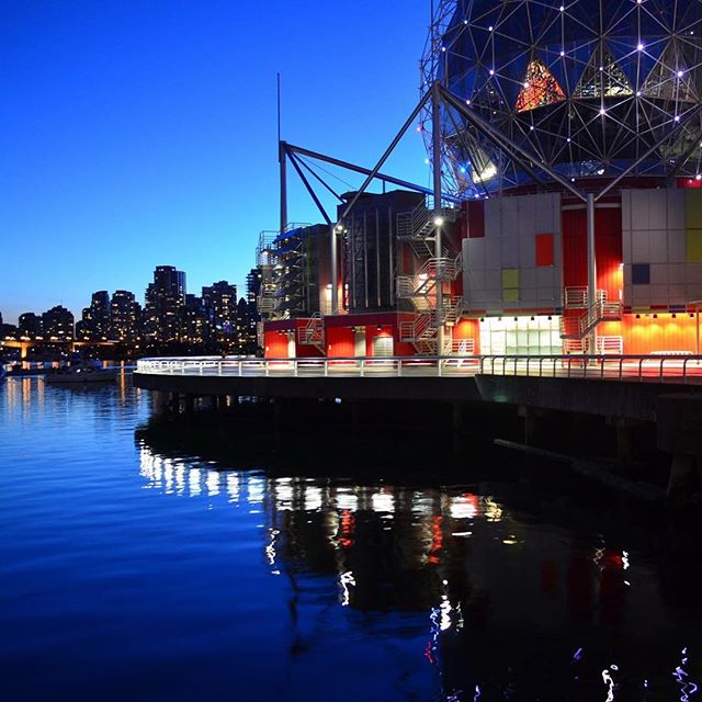 Science World in Vancouver, British Columbia, glows at night with city lights reflecting in the calm water.