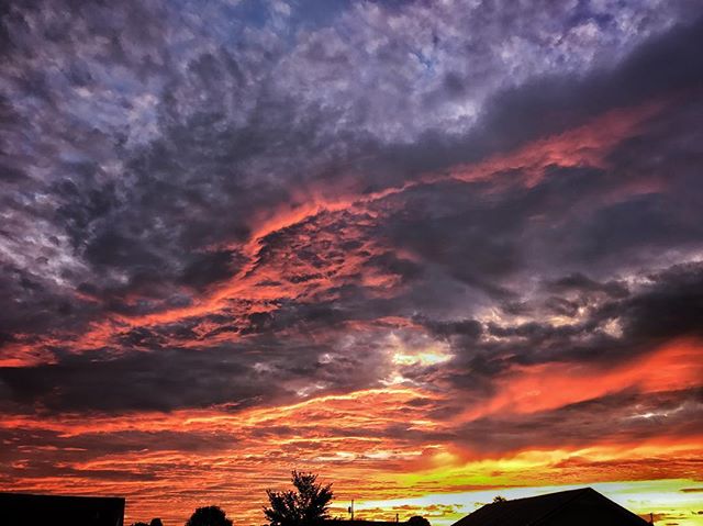 A dramatic sky featuring colorful clouds at sunset creates a peaceful countryside atmosphere.