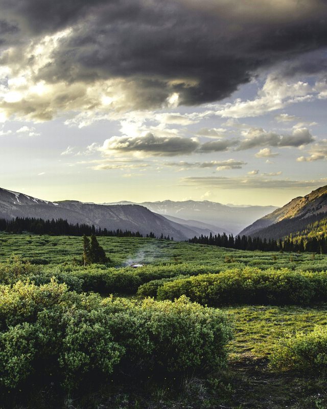 A serene landscape featuring green meadows and distant mountains under a cloudy sky, perfect for nature and travel themes.