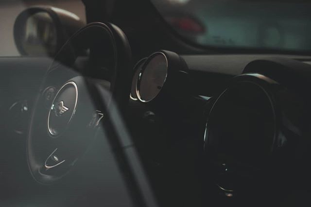 A close-up of a Mini Cooper's steering wheel and dashboard, showcasing its modern design.