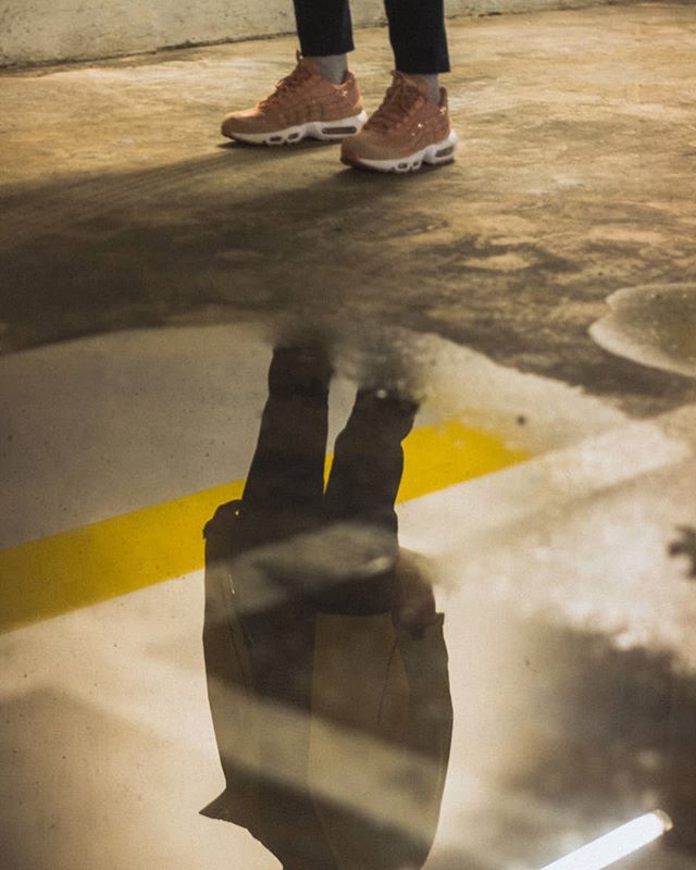 Reflection of a person wearing sneakers standing in a puddle, creating an urban and artistic image.