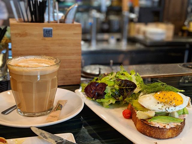A coffee, egg toast, and salad are on a table in a cafe, perfect for a delicious and relaxing breakfast.