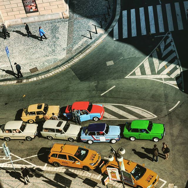 Aerial view of a city street with colorful vintage cars and taxis parked at an intersection.