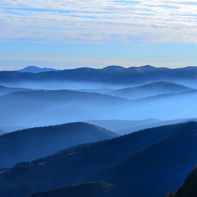 A scenic mountain range with a misty blue overlay creates a serene and calming landscape, ideal for travel and tourism promotions.