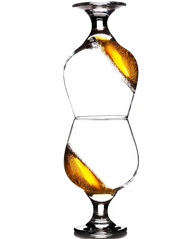 Two stacked glasses containing a golden liquid create a visually striking and elegant composition against a white backdrop.