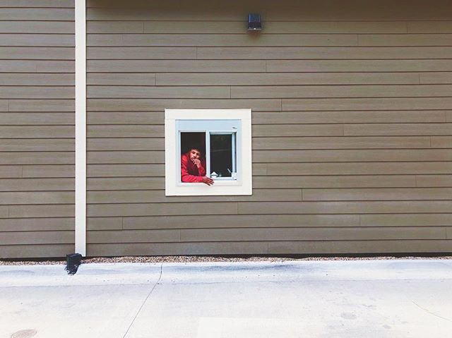 A man peers out of a window in a modern building, creating a minimalist and contemplative scene.