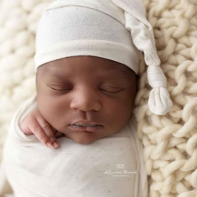 A newborn baby peacefully sleeps wearing a soft white hat wrapped in a blanket. Perfect for baby product advertisements.