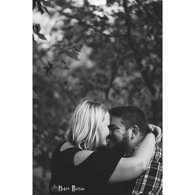 A couple embraces tenderly in a black and white outdoor photo, showcasing intimacy and affection.
