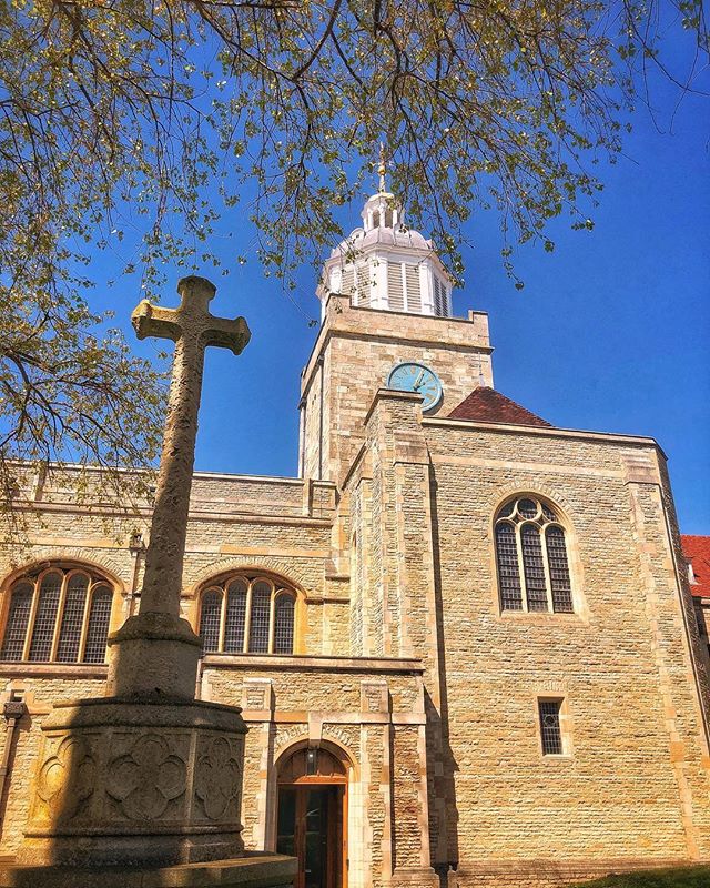 A stone church and cross stand tall under a blue sky, showcasing classic architecture and serene beauty.