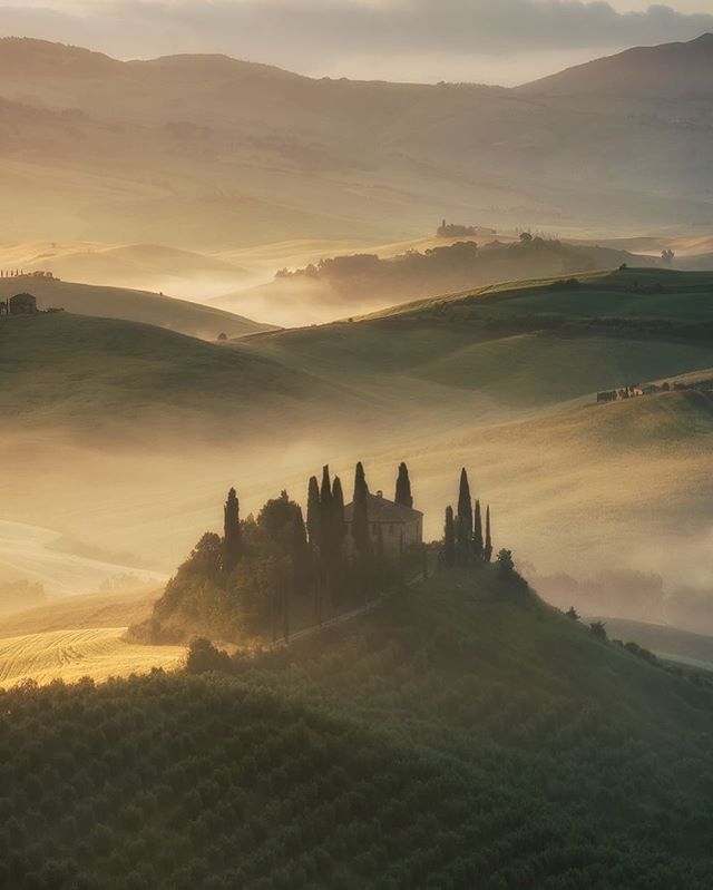 A tranquil Tuscan landscape with a house nestled among rolling hills, bathed in soft morning light and mist.