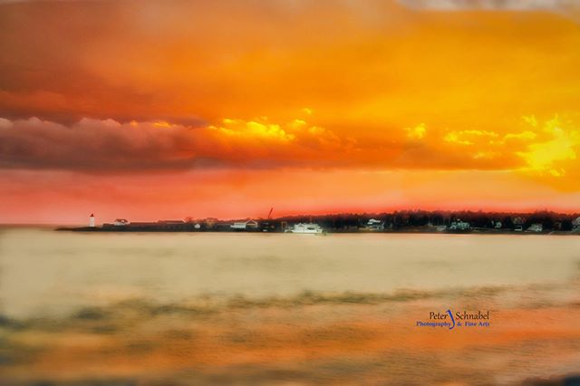 A tranquil coastal scene featuring a lighthouse, boats, and a serene waterfront under a warm sunset sky.