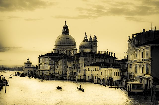 A sepia-toned cityscape showcases Venice's Grand Canal, featuring the Santa Maria della Salute church and a gondola on the water.