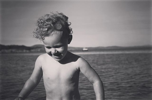 A happy child laughs while playing in the water on a sunny day at the beach.