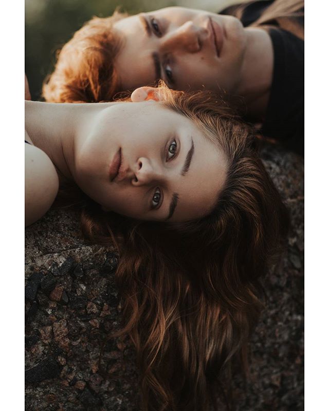 Two women with red and brown hair lie side by side in a dreamy outdoor setting, perfect for beauty or wellness campaigns.