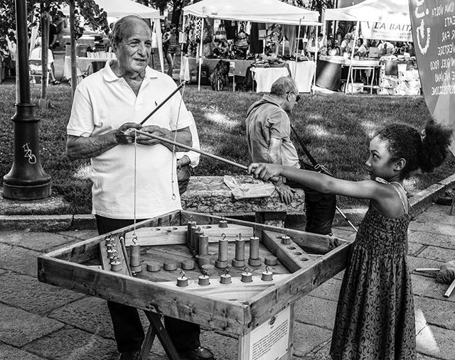 A girl plays a game with an older man in a park, enjoying an outdoor recreational activity.