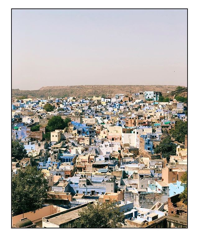 Aerial view of a densely packed city showing blue and beige buildings under a soft, diffused light.